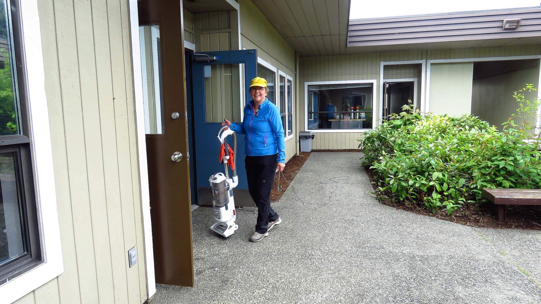 Parksville Community Centre volunteer smiling near the centre with vacuum cleaner